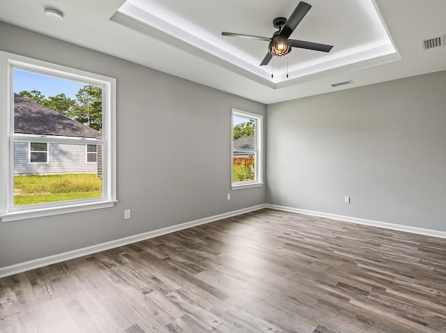 unfurnished room featuring a raised ceiling, ceiling fan, and hardwood / wood-style floors