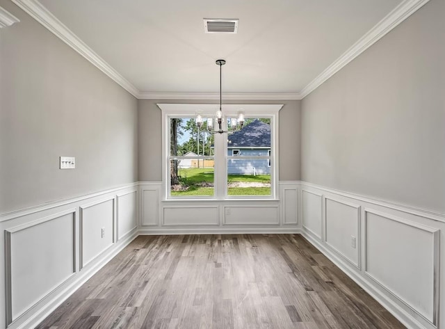 unfurnished dining area featuring an inviting chandelier, ornamental molding, and light hardwood / wood-style flooring