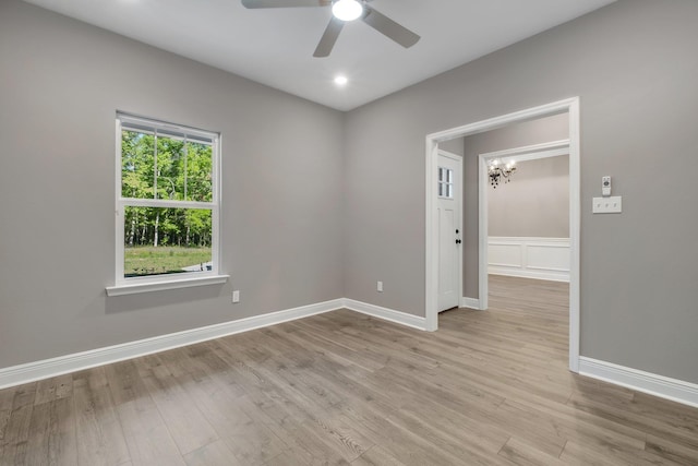 empty room featuring light wood-style floors, baseboards, recessed lighting, and ceiling fan with notable chandelier