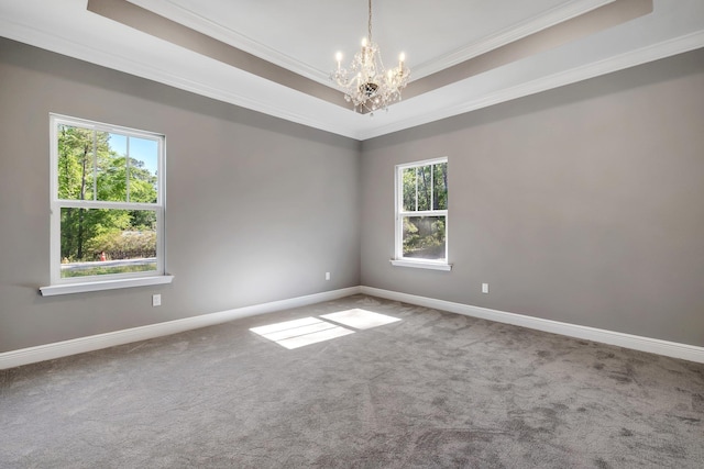 carpeted empty room with an inviting chandelier, a healthy amount of sunlight, ornamental molding, and baseboards