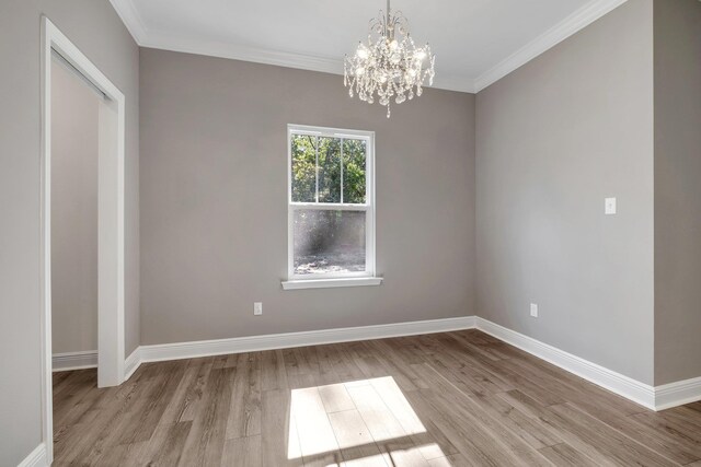 unfurnished room featuring ornamental molding, an inviting chandelier, baseboards, and light wood-type flooring