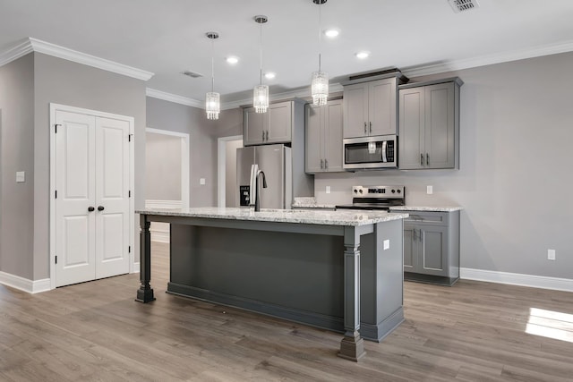 kitchen featuring gray cabinets, wood finished floors, appliances with stainless steel finishes, baseboards, and a center island with sink