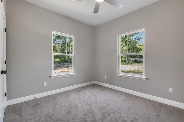 carpeted spare room featuring ceiling fan and baseboards