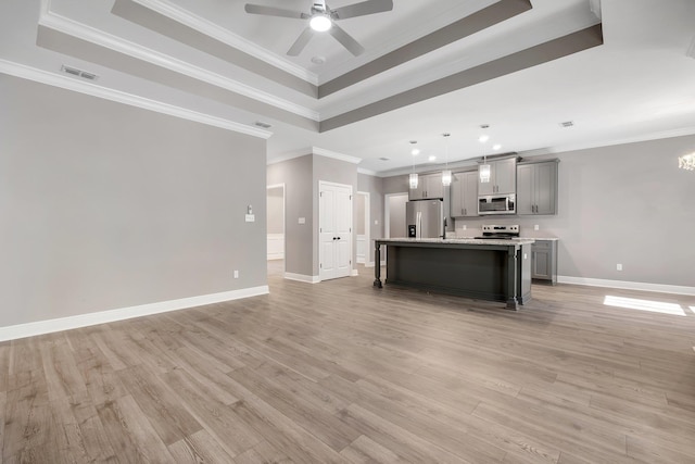 unfurnished living room featuring a raised ceiling, light wood-style floors, baseboards, ornamental molding, and ceiling fan with notable chandelier