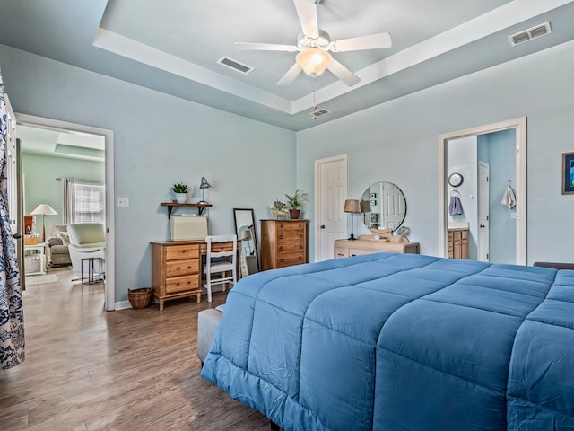 bedroom featuring ensuite bathroom, ceiling fan, a raised ceiling, and dark hardwood / wood-style floors