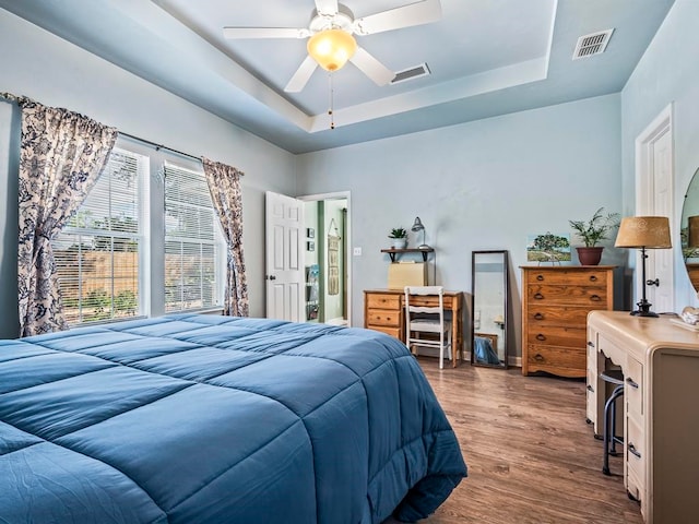 bedroom featuring hardwood / wood-style floors, ceiling fan, and a raised ceiling