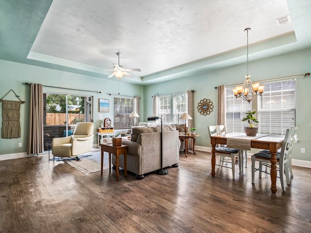 living room with dark hardwood / wood-style flooring, a healthy amount of sunlight, and a raised ceiling