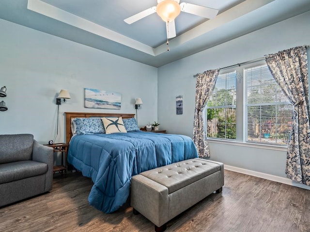 bedroom featuring dark hardwood / wood-style flooring, ceiling fan, and a raised ceiling