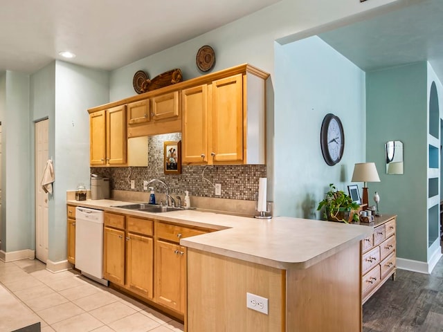 kitchen featuring backsplash, light tile patterned floors, sink, dishwasher, and kitchen peninsula