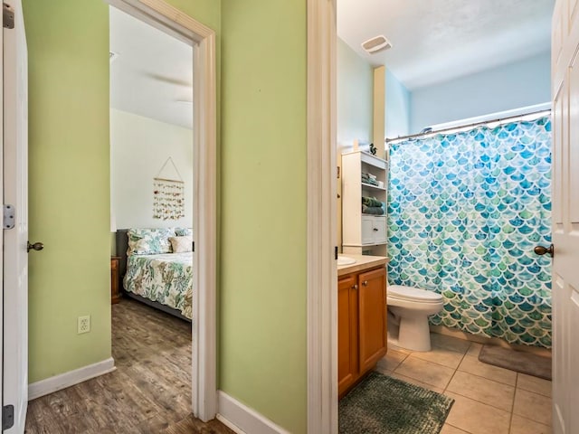 bathroom with toilet, vanity, hardwood / wood-style flooring, and curtained shower