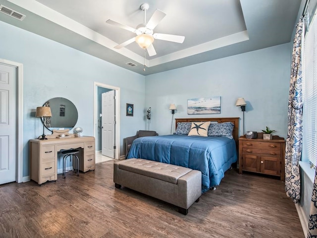 bedroom featuring ceiling fan, a tray ceiling, and dark hardwood / wood-style floors