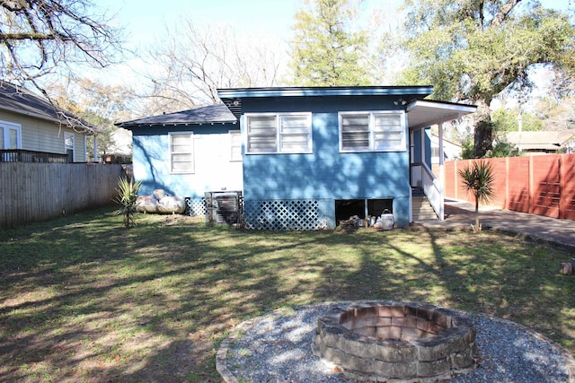 back of house featuring an outdoor fire pit and a lawn