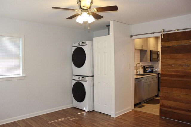 washroom with a barn door, sink, dark hardwood / wood-style floors, and stacked washer and clothes dryer