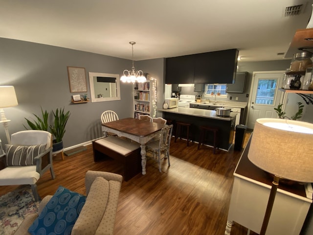 dining area with dark wood-style floors, visible vents, a notable chandelier, and baseboards