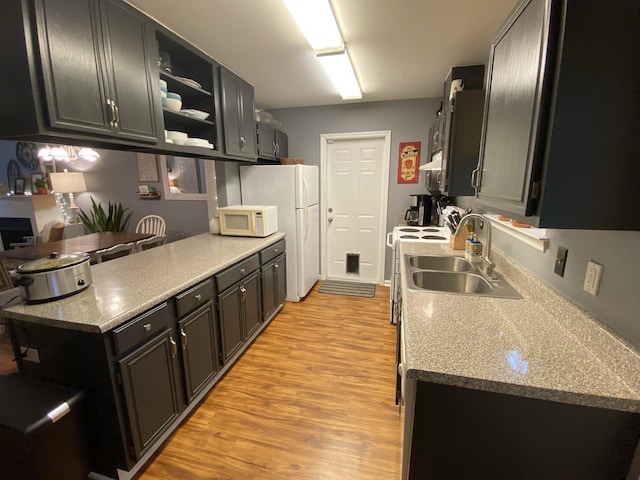 kitchen featuring white appliances, dark cabinets, open shelves, and a sink