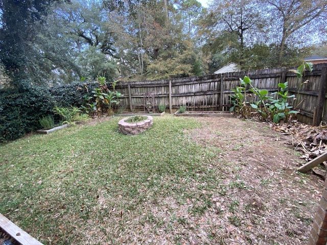 view of yard featuring a fenced backyard and a fire pit