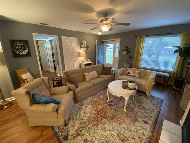 living room featuring a ceiling fan, baseboards, visible vents, and wood finished floors