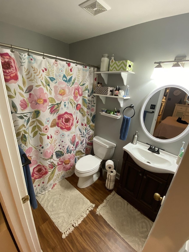 full bath with toilet, visible vents, wood finished floors, and vanity