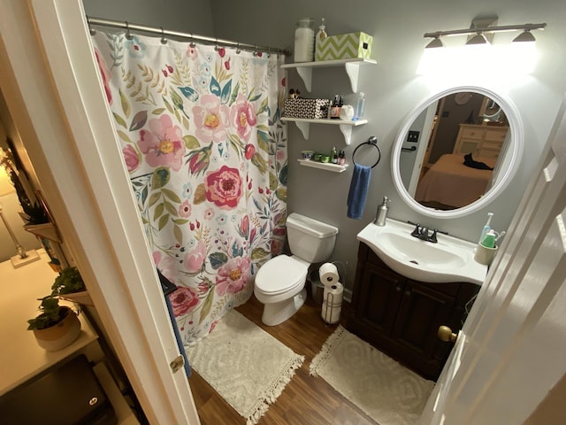 bathroom featuring toilet, curtained shower, wood finished floors, and vanity