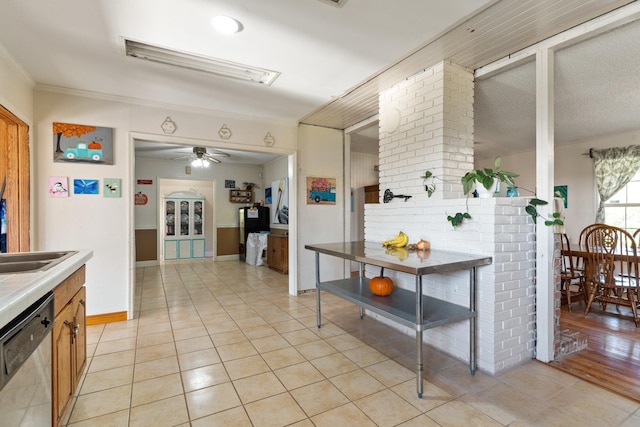 kitchen featuring brown cabinets, crown molding, light tile patterned floors, light countertops, and dishwasher