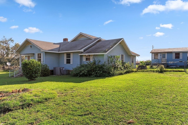 view of side of property with a lawn, a chimney, and fence