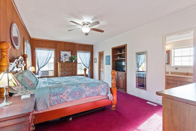 bedroom with a textured ceiling, carpet floors, wood walls, and multiple windows