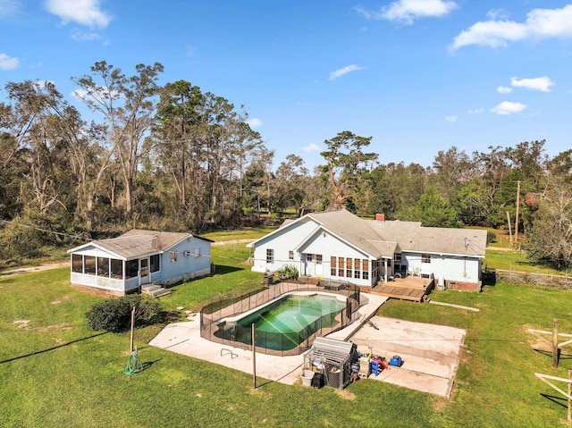 rear view of property featuring a deck, a sunroom, a yard, an outdoor pool, and a patio area