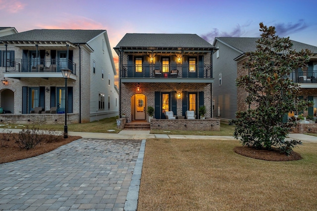 view of front facade featuring a balcony and a lawn