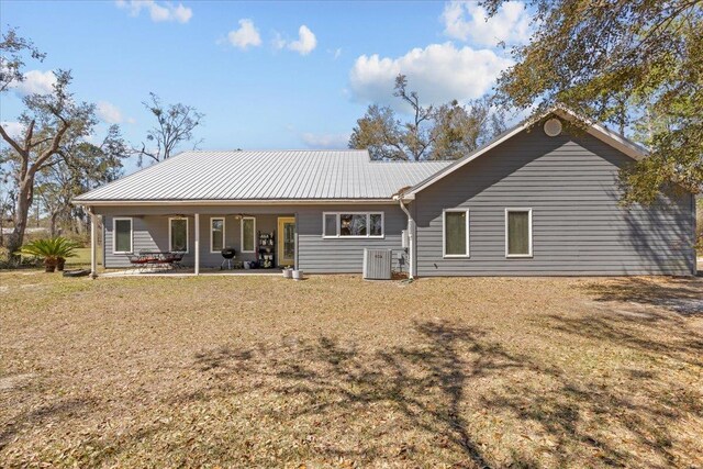 back of property featuring central air condition unit, a patio area, a lawn, and metal roof