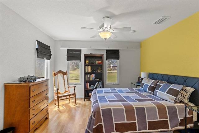 bedroom with visible vents, ceiling fan, baseboards, and wood finished floors