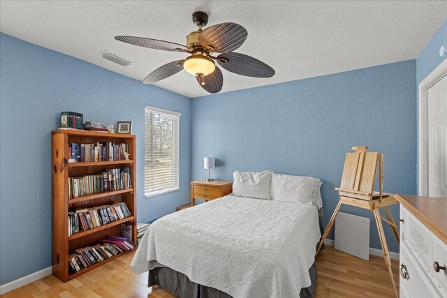 bedroom featuring visible vents, baseboards, light wood-style floors, and ceiling fan