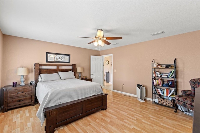 bedroom with light wood finished floors, visible vents, and baseboards