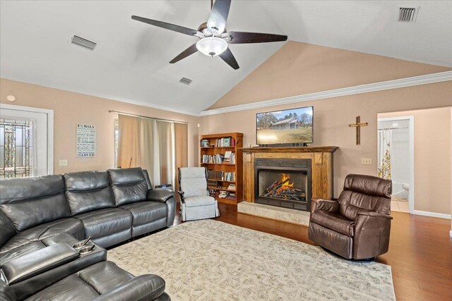 living area with visible vents, a lit fireplace, and wood finished floors