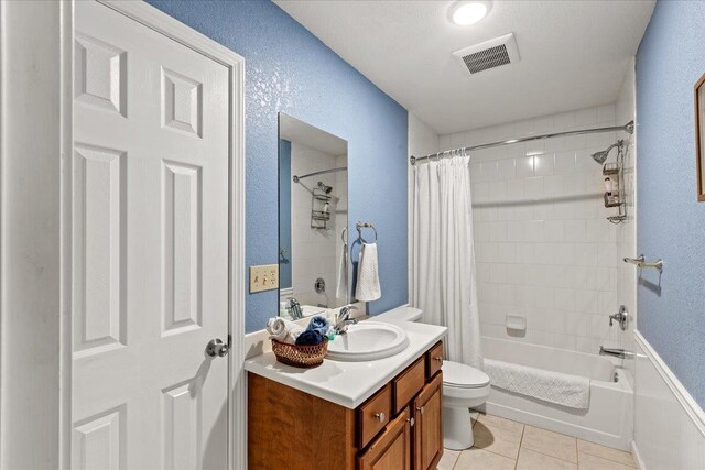 full bath with visible vents, toilet, shower / bath combo with shower curtain, tile patterned floors, and vanity