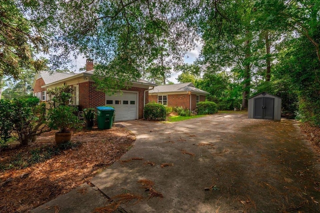 921 Forest Dr, Quincy, FL 32351 - view of front of home featuring a garage, asphalt driveway, a storage unit, brick siding, and a chimney