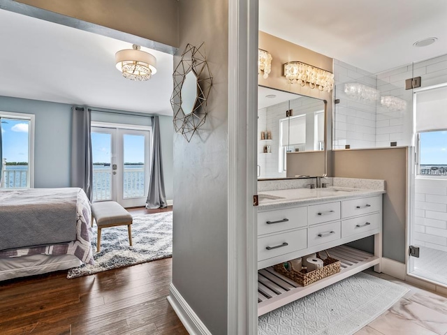 bathroom featuring ensuite bathroom, french doors, vanity, a shower stall, and baseboards