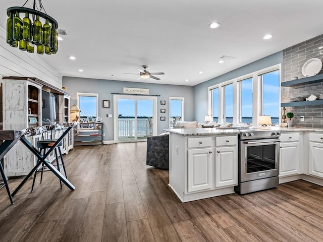 kitchen featuring high end range, open floor plan, dark wood-style flooring, white cabinetry, and light stone countertops