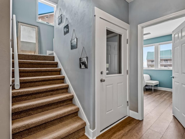 stairs featuring plenty of natural light, wood finished floors, and baseboards