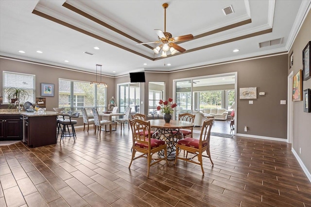 dining room with ceiling fan, dark hardwood / wood-style floors, crown molding, and a tray ceiling