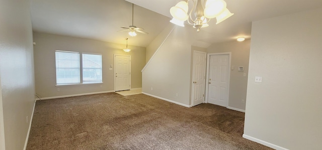 carpeted empty room featuring ceiling fan with notable chandelier and vaulted ceiling