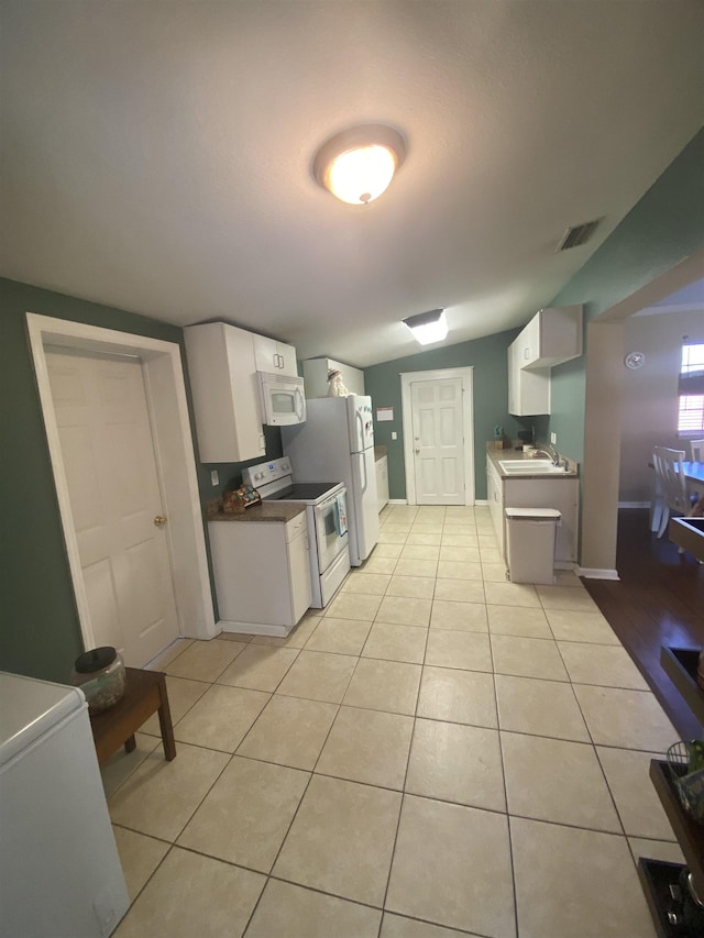 kitchen with sink, white appliances, light tile patterned floors, and white cabinets