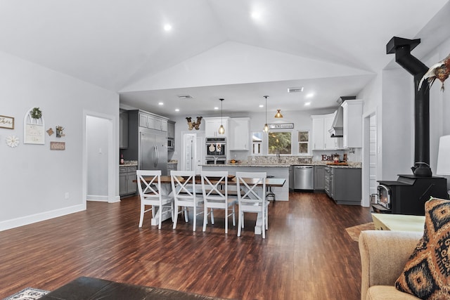 dining room featuring lofted ceiling, dark hardwood / wood-style floors, and a wood stove