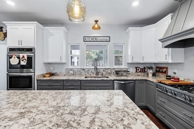 kitchen with stainless steel appliances, sink, white cabinets, and custom range hood