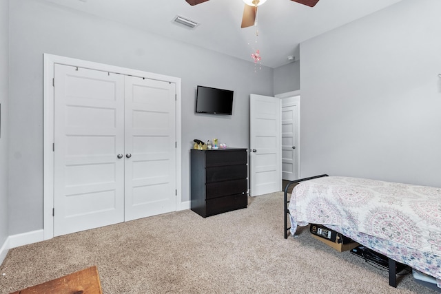 bedroom featuring light colored carpet, ceiling fan, and a closet