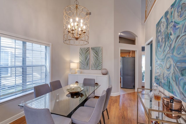 dining space featuring a high ceiling, a chandelier, and light wood-type flooring