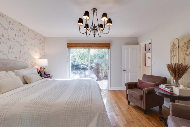 bedroom with a notable chandelier, light wood-type flooring, and access to outside