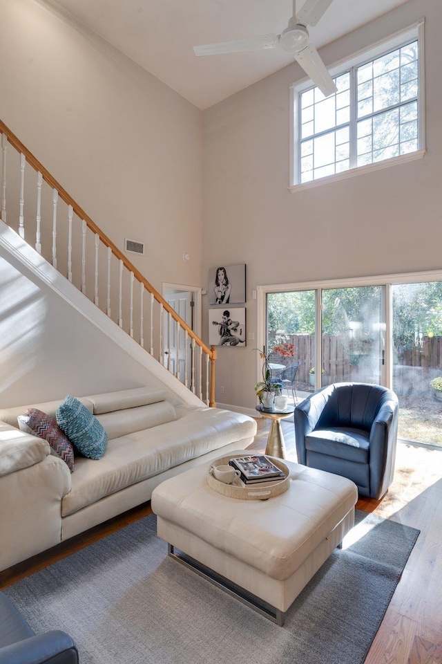 living room featuring a towering ceiling, ceiling fan, and hardwood / wood-style flooring