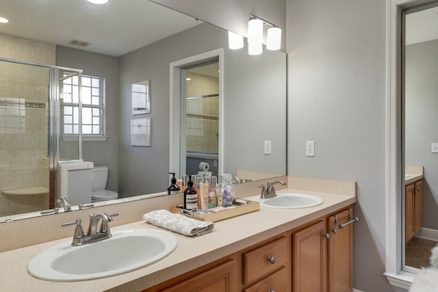 bathroom with toilet, an enclosed shower, and vanity