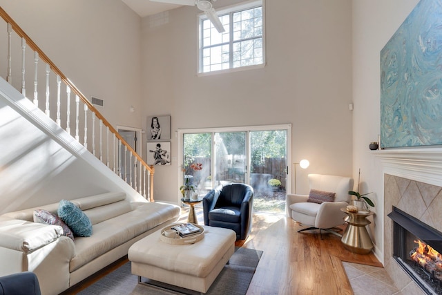 living room featuring light wood-type flooring, a towering ceiling, and a fireplace