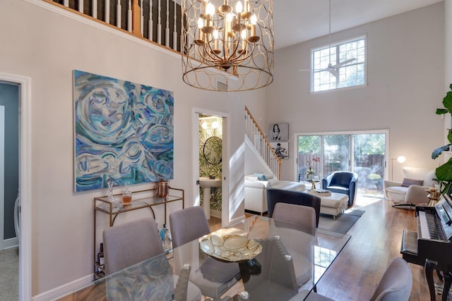 dining space featuring a towering ceiling, a chandelier, and hardwood / wood-style floors